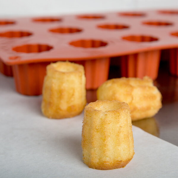 A group of small cakes next to a Matfer Bourgeat orange silicone mold.