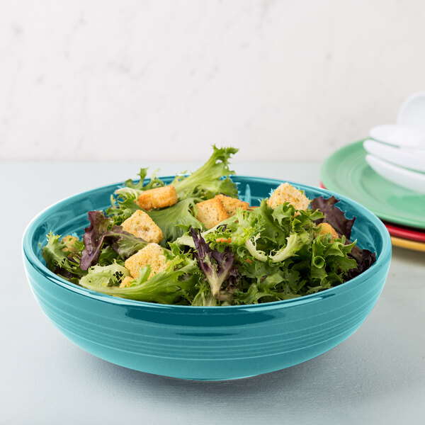 A Fiesta turquoise china bistro bowl filled with salad and croutons.