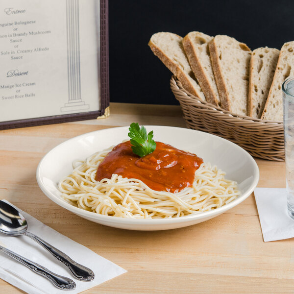 A Tuxton eggshell china bowl filled with spaghetti and sauce on a table.