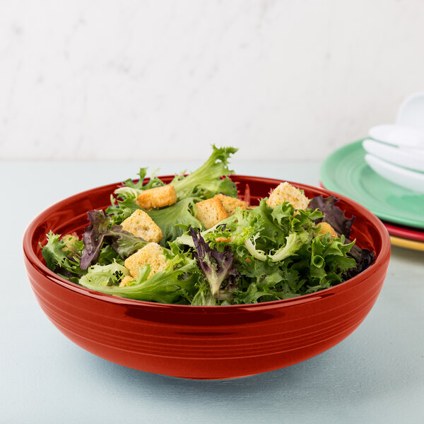 A Fiesta Scarlet china bistro bowl filled with salad on a table.