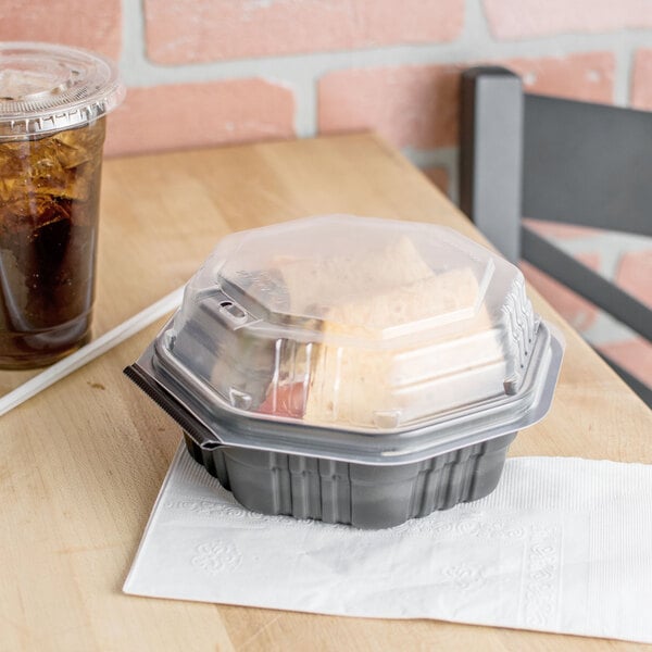 A Solo OctaView Supreme plastic take-out container with food on a table.