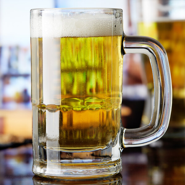 An Anchor Hocking beer mug full of beer on a table.