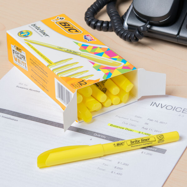 A Bic box of 12 fluorescent yellow highlighters with one on a receipt.