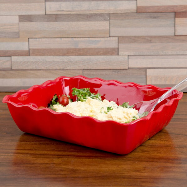 A red Cambro deli crock with food in it and a spoon.