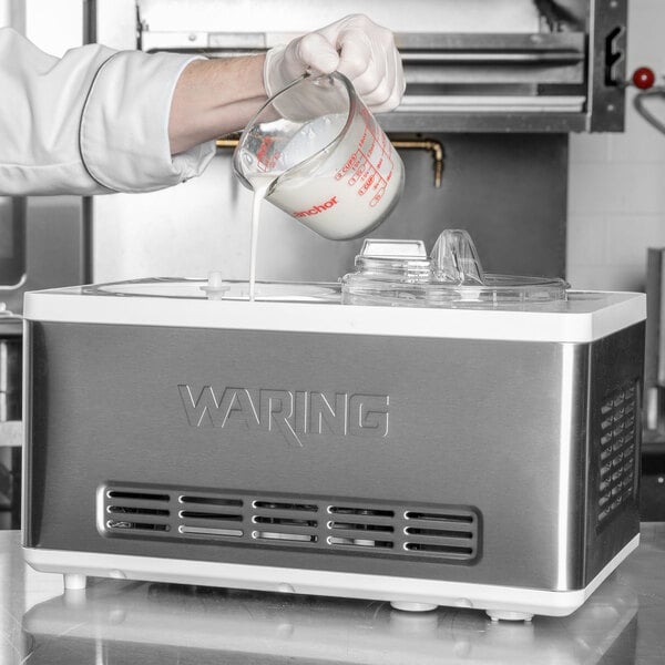A person pouring milk into a Waring ice cream maker.