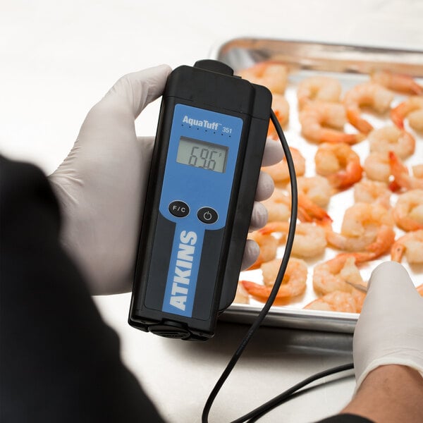 A person using a Cooper-Atkins AquaTuff Wrap&Stow Thermocouple Thermometer to measure the temperature of a shrimp.