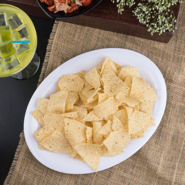 A Carlisle white melamine platter with chips on a table.