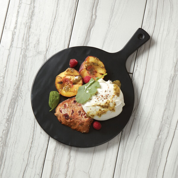 An American Metalcraft black faux slate melamine serving peel with a round plate of ice cream and peaches on a table.
