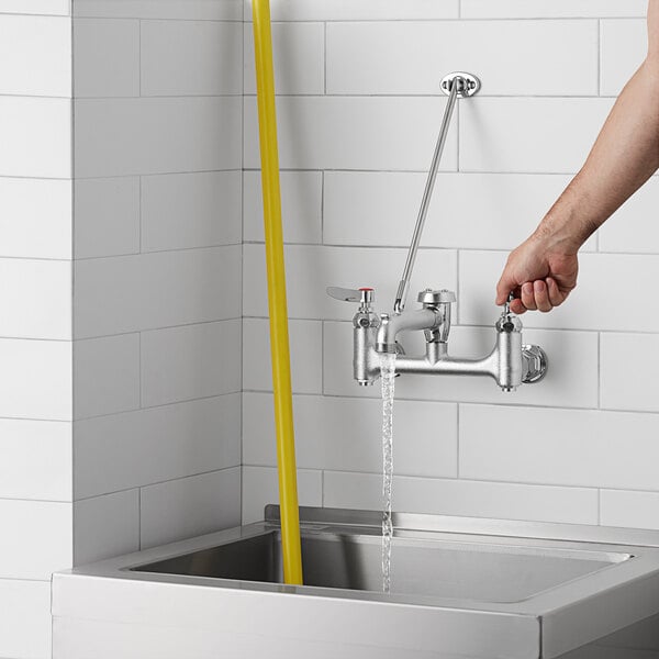 A person using a T&S Mop Sink Faucet to fill a yellow bucket.