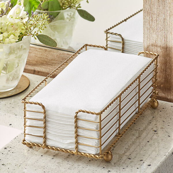 A napkin holder with white Hoffmaster Linen-Like guest towels on a counter.