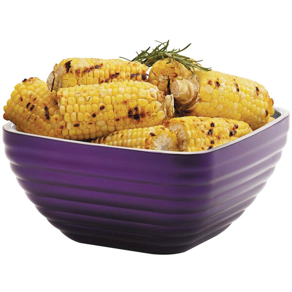 A Vollrath passion purple metal bowl filled with corn on the cob.
