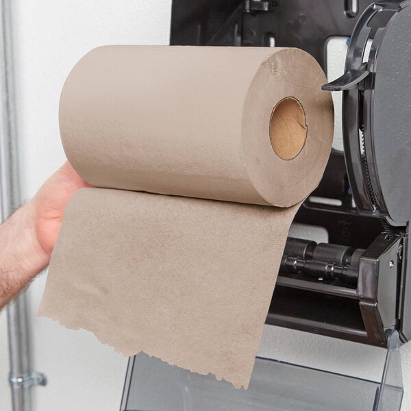 A hand holding a roll of Lavex Natural Kraft hardwound paper towels.