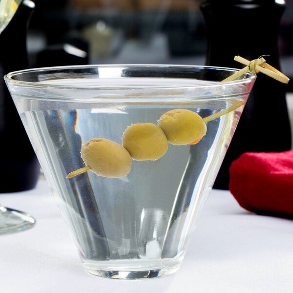 A Libbey stemless martini glass with olives floating in it.