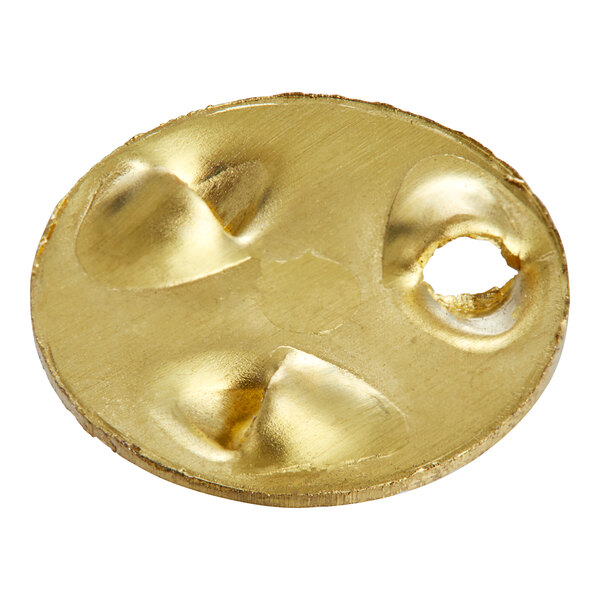 A gold plated metal Scotsman Spinner with holes on a table in a bar.
