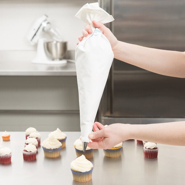 A person using an Ateco Polyurethane coated pastry bag to frost cupcakes.