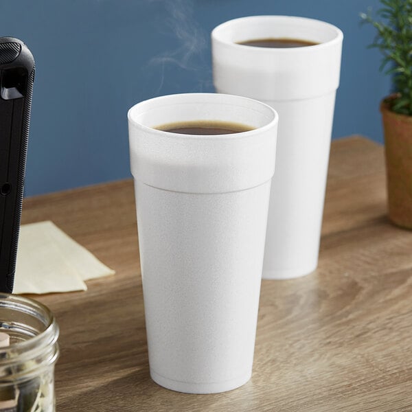 Two white Dart foam cups of coffee on a table.