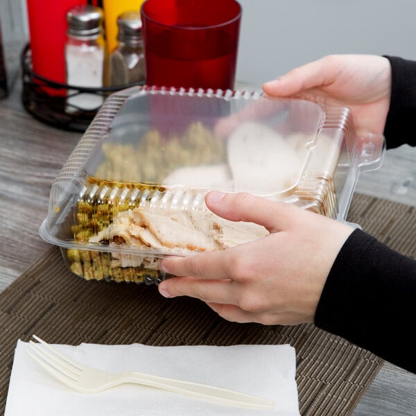 A person holding a Duralock clear hinged plastic container of food.