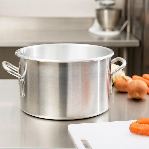 A Vollrath Wear-Ever aluminum sauce pot on a counter with carrots.