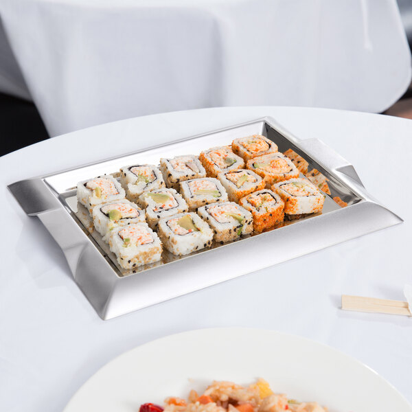 A Vollrath stainless steel serving tray with sushi on a table.