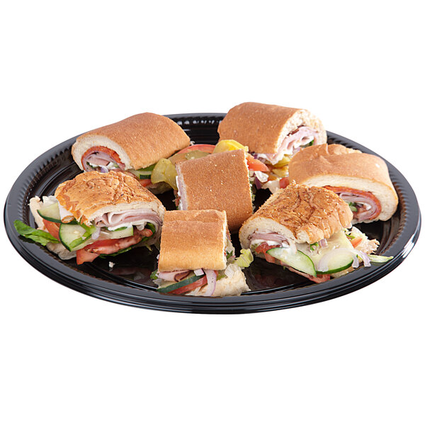 A WNA Comet black plastic catering tray with sandwiches on it.