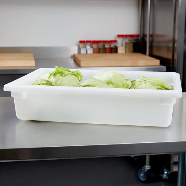A white Carlisle food storage container filled with lettuce.