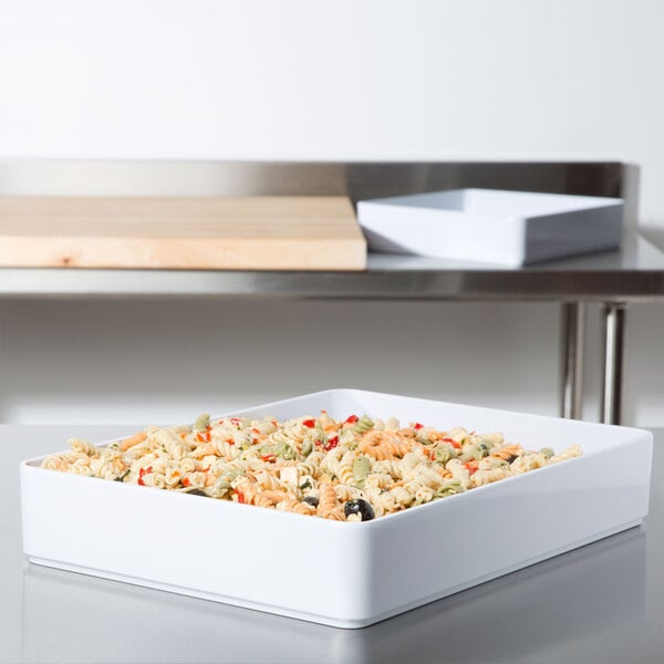 A white rectangular GET Milano deli crock filled with pasta, olives, and peppers on a counter.