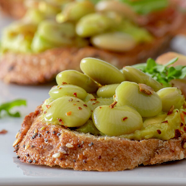 A plate of bread with a pile of Allens Lima Beans on the side.