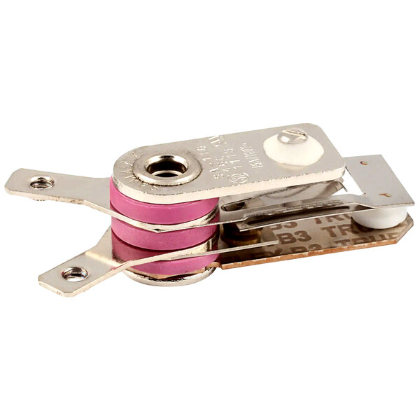 A close up of a metal and pink snap action bi-metal thermostat.