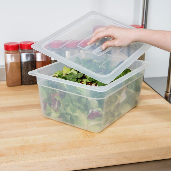A hand using a Cambro translucent plastic lid to open a container of salad.