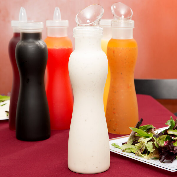 A salad with dressing in a frosted bottle with a white lid.