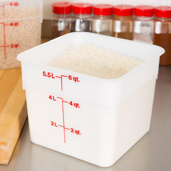 A white Cambro food storage container filled with rice in a measuring cup.