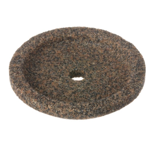 A circular brown grinding stone with a hole in the middle.