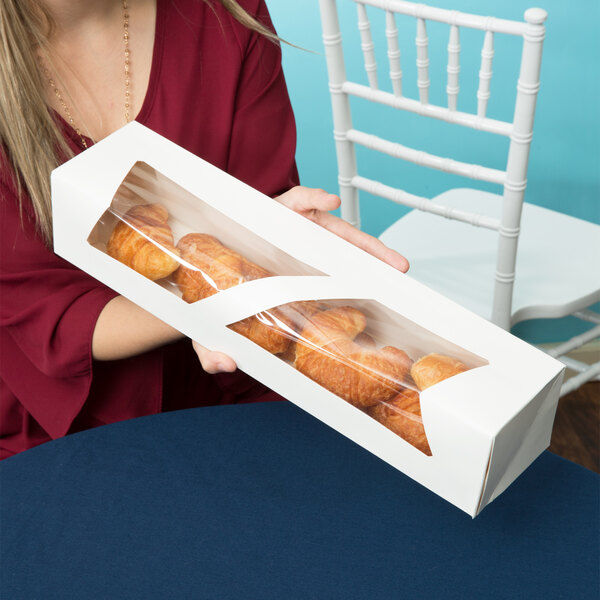 A woman holding a white auto-popup window box of donuts.
