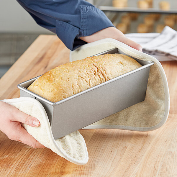 A person holding a Chicago Metallic Pullman loaf pan with a loaf of bread inside.