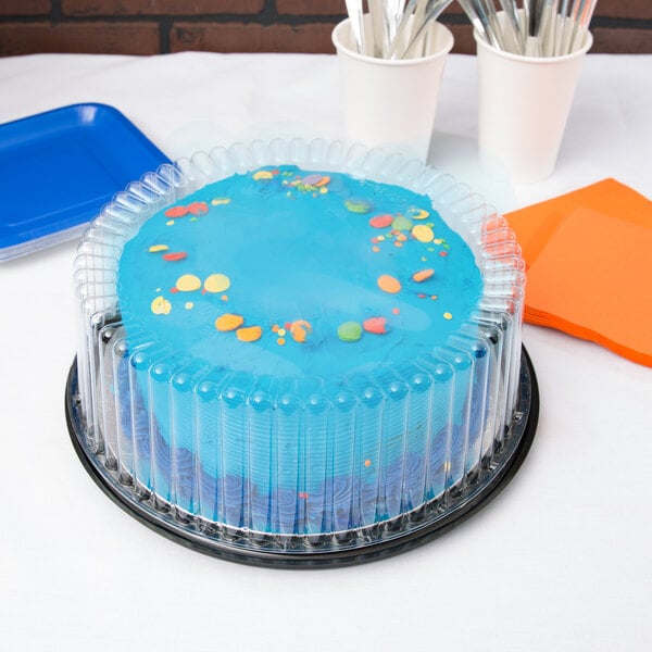 A blue cake with blue frosting and a plastic cover on a table.