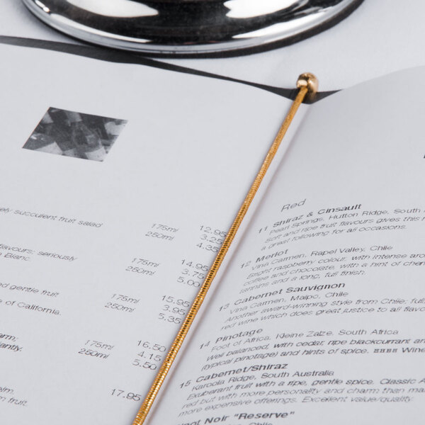 A black menu book with a gold elastic band on a table.