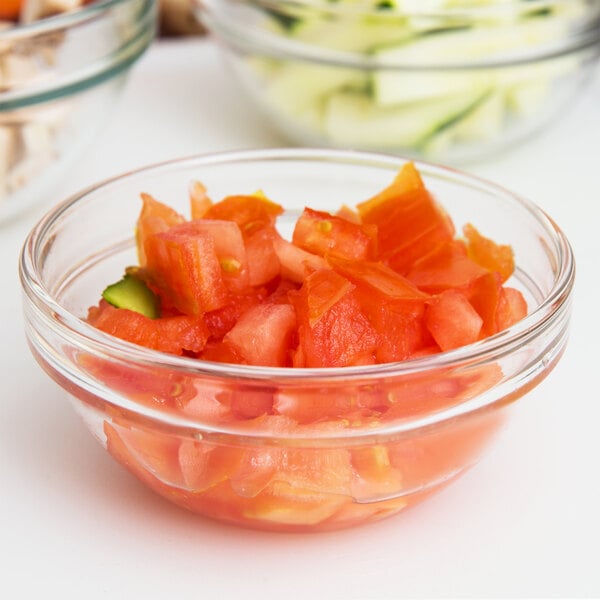 An Arcoroc glass bowl filled with diced tomatoes.