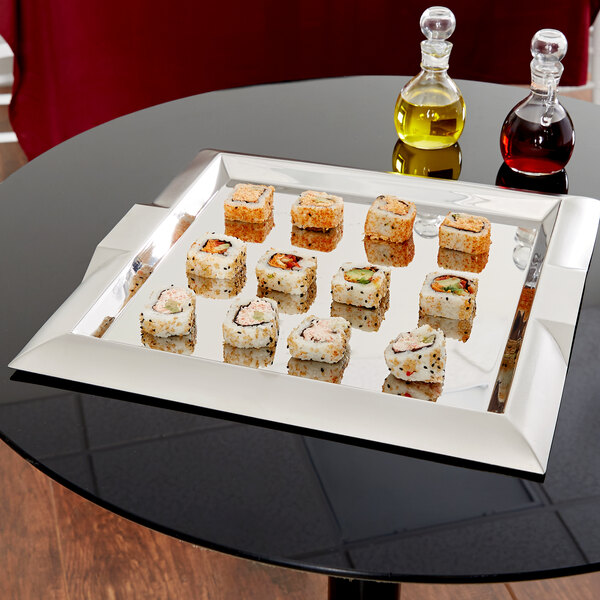 A Vollrath square stainless steel serving tray with sushi on a table.