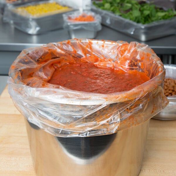 A plastic bag of red sauce in a container.