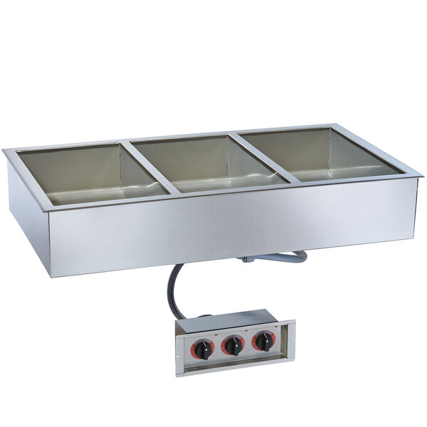 A stainless steel food pan with three compartments in a stainless steel drop-in hot food well.