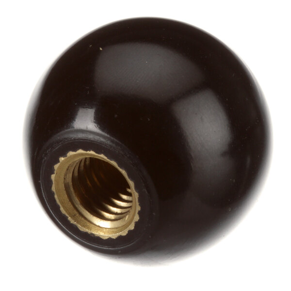 A black ball with a gold nut threaded onto it.