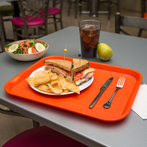 An orange Carlisle fast food tray holding a sandwich, salad, and a glass of iced tea.