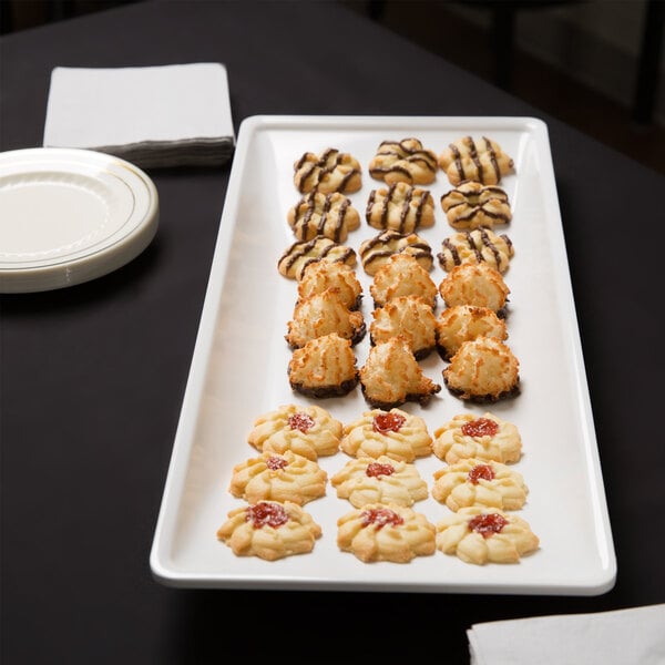 An American Metalcraft trapezoid melamine serving platter with cookies and pastries on a table.