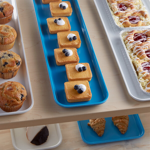 A blue Cambro market tray of pastries on a bakery display counter.