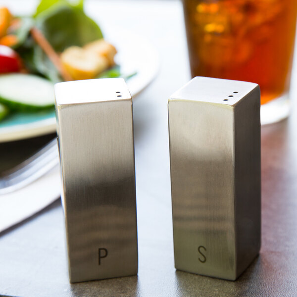 A couple of Tablecraft stainless steel salt and pepper shakers on a table.