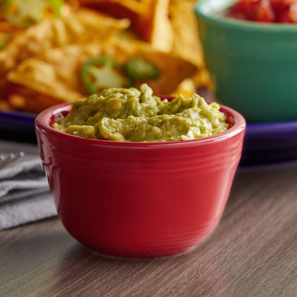 A red Tuxton China bouillon bowl filled with guacamole and tortilla chips.