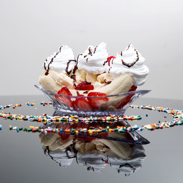 A clear banana split dish with a scoop of ice cream, a banana, and a strawberry.