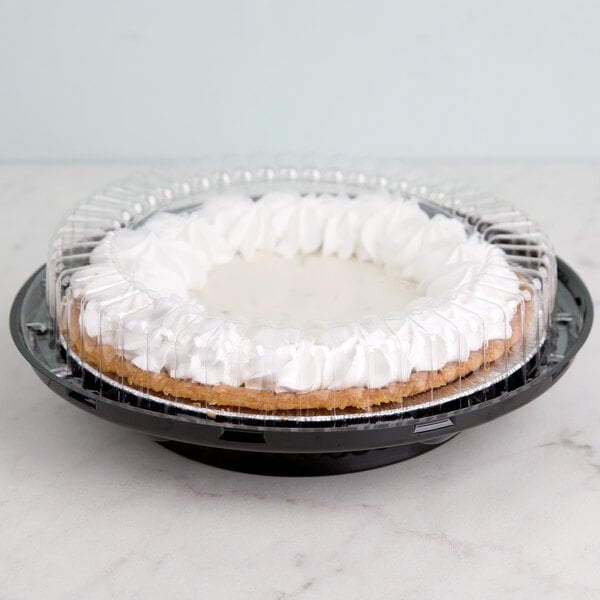 A pie with whipped cream on top in a black plastic container with a clear lid.