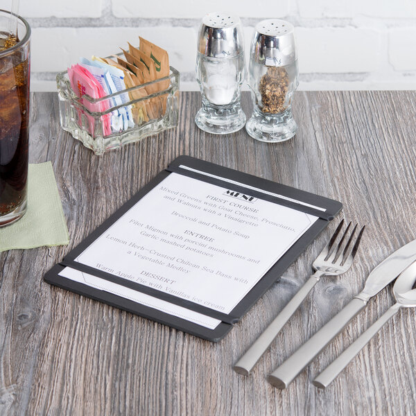 A black Cal-Mil menu board with silver flex bands on a table with silverware and a glass of water.