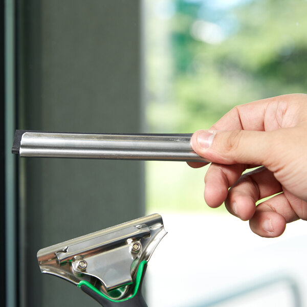 A hand using a Unger ErgoTec squeegee blade to clean a glass door.